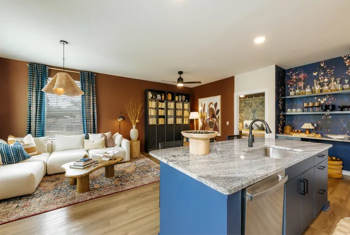 Chic open-plan living room with cozy white sectional, stylish rug, modern lighting, and elegant kitchen island.