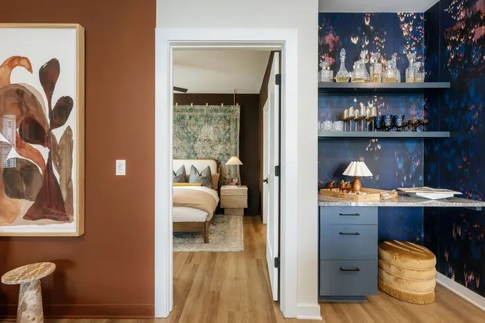 Chic and cozy apartment interior showcasing a warm-toned bedroom with artistic decor, elegant wall art, and a stylishly adorned shelving area.