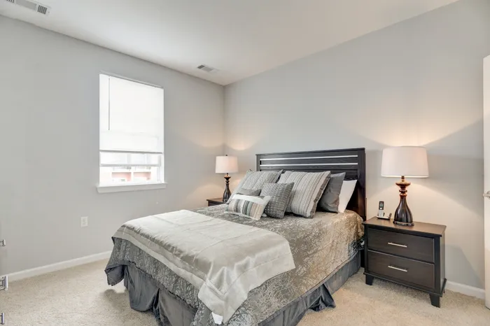 Elegant bedroom with a cozy queen-sized bed, stylish decor, and soft natural light, perfect for relaxation.