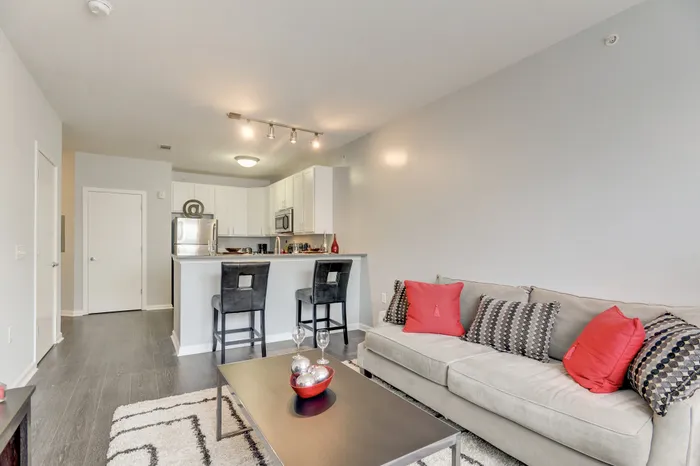 Chic open-plan living area with a modern kitchen, stylish breakfast bar, and cozy sofa, perfect for relaxation and entertaining.
