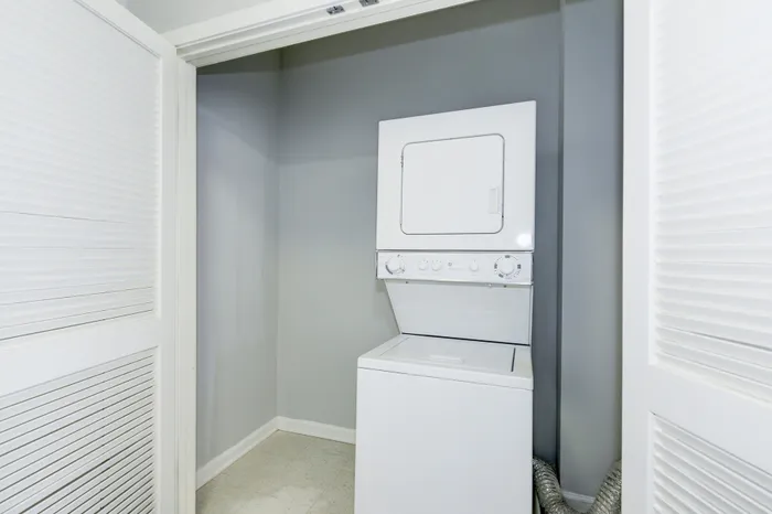 Modern apartment laundry area with sleek stacked washer and dryer in a compact, stylish alcove.