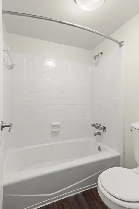 Bright, modern bathroom featuring a pristine white bathtub with tiled walls and elegant fixtures, offering a serene and relaxing atmosphere.