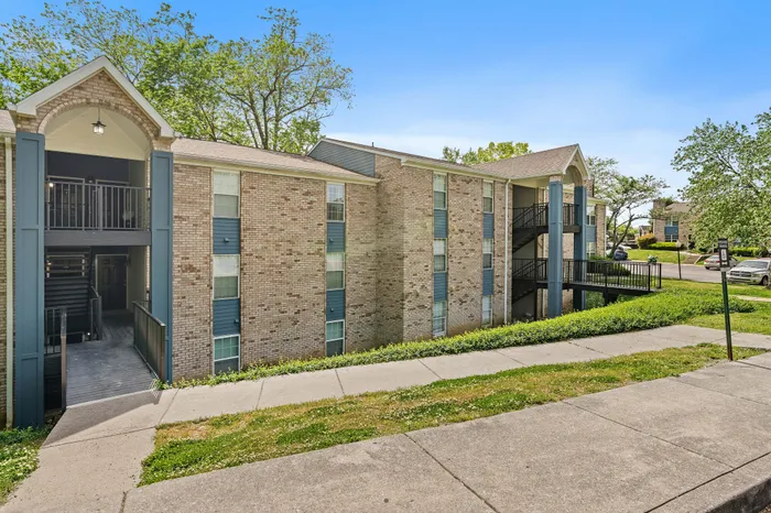 Charming apartment building with brick exterior and modern staircases, set in a lush, green neighborhood.