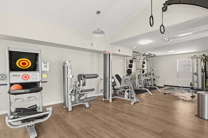 Modern apartment gym featuring state-of-the-art exercise equipment, sleek wooden flooring, and a bright, inviting atmosphere.