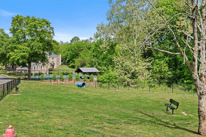 Charming green space with lush trees, a pathway, and a serene setting in a residential area, perfect for relaxation and outdoor activities.