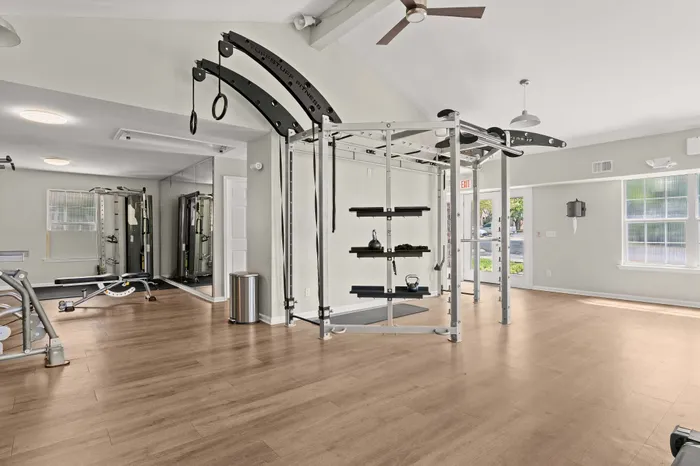 Modern fitness center with state-of-the-art equipment and sunlit windows, featuring sleek wooden flooring.