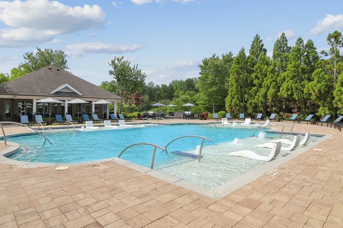 Inviting outdoor swimming pool with sleek lounge chairs and lush greenery, offering a tranquil oasis for relaxation.