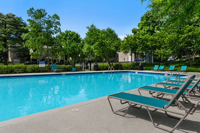 Inviting outdoor swimming pool area with comfortable lounge chairs surrounded by lush greenery, perfect for relaxation and leisure.