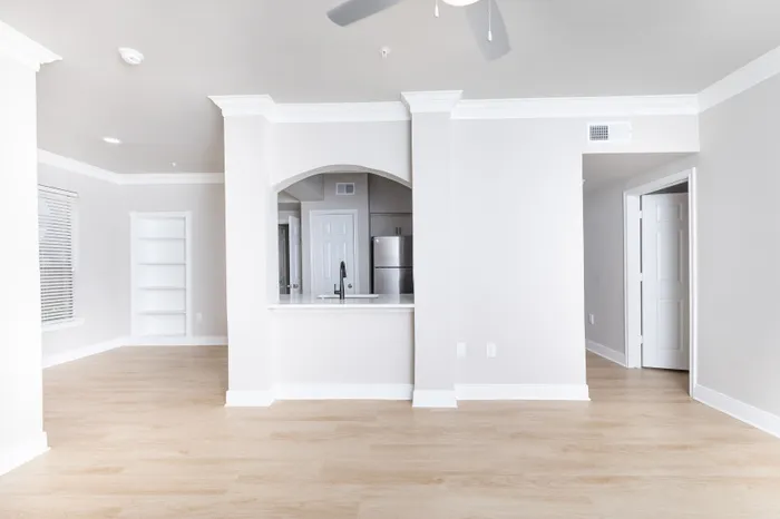 Bright and modern apartment interior with spacious living area, sleek hardwood floors, and open-plan kitchen featuring elegant archway and stainless steel accents.