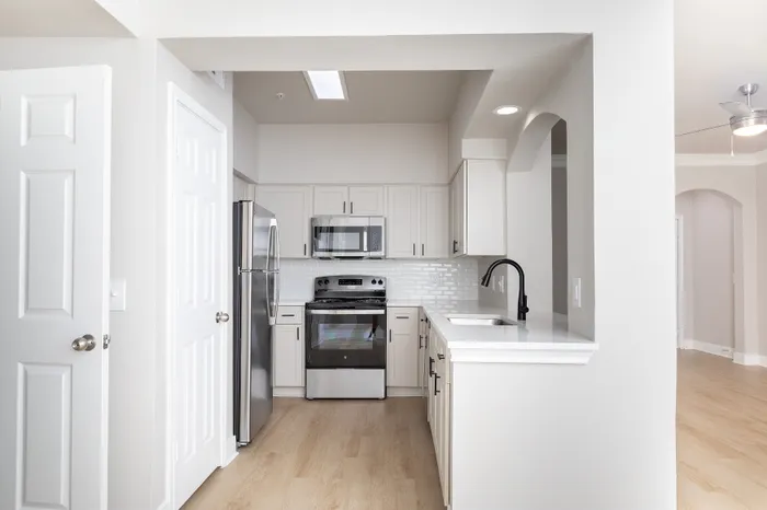 Modern kitchen with sleek stainless steel appliances, white cabinetry, and elegant open design.