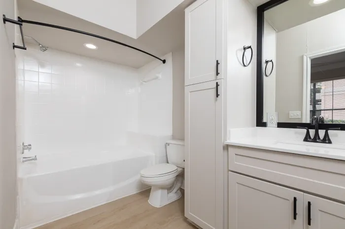 Elegant bathroom with modern white cabinetry, sleek fixtures, and a pristine bathtub offers a serene retreat.