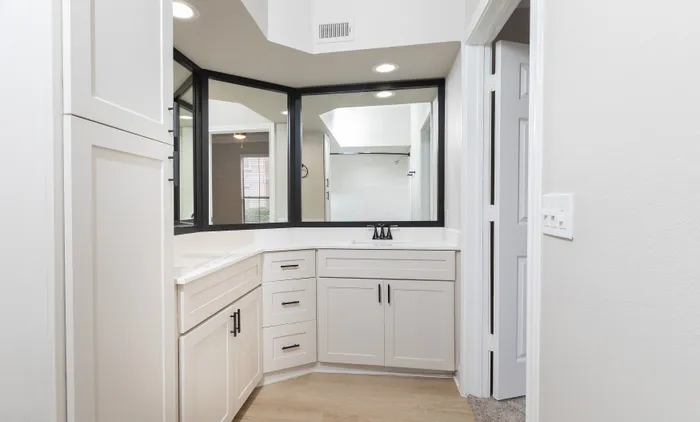 Chic bathroom with elegant white cabinetry, modern fixtures, and ample counter space under bright lighting.