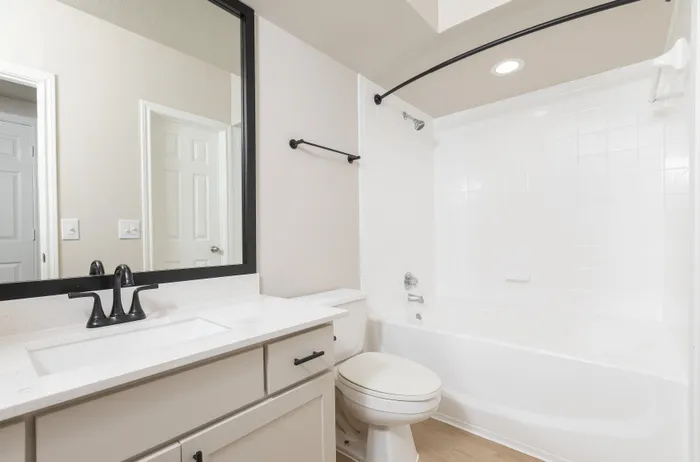 Modern bathroom with sleek white vanity, large mirror, and elegant bathtub.