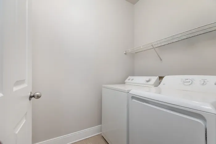 Modern laundry room with white appliances and ample shelving, offering convenience and style.