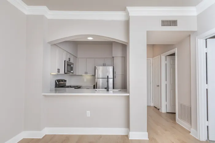 Modern kitchen with sleek stainless steel appliances, elegant white cabinetry, and a stylish open layout featuring hardwood floors and a breakfast bar.