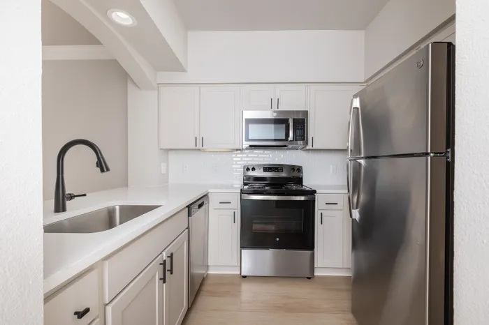 Modern kitchen featuring sleek stainless steel appliances, elegant white cabinetry, and a bright subway tile backsplash.