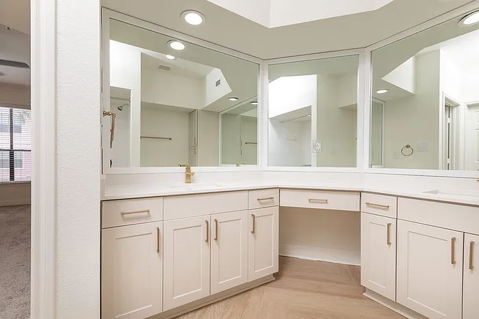 Luxurious bathroom with elegant L-shaped vanity, expansive mirrors, and sleek wood cabinets.