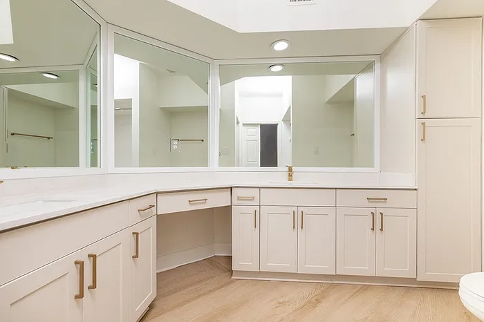 Elegant bathroom with modern cabinetry, large mirrors, and warm wood flooring, ideal for luxury living.