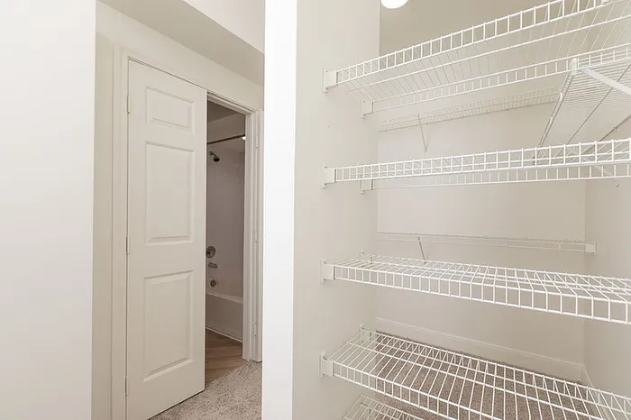 Inviting closet with ample wire shelving adjacent to a bathroom entrance, perfect for organized living.