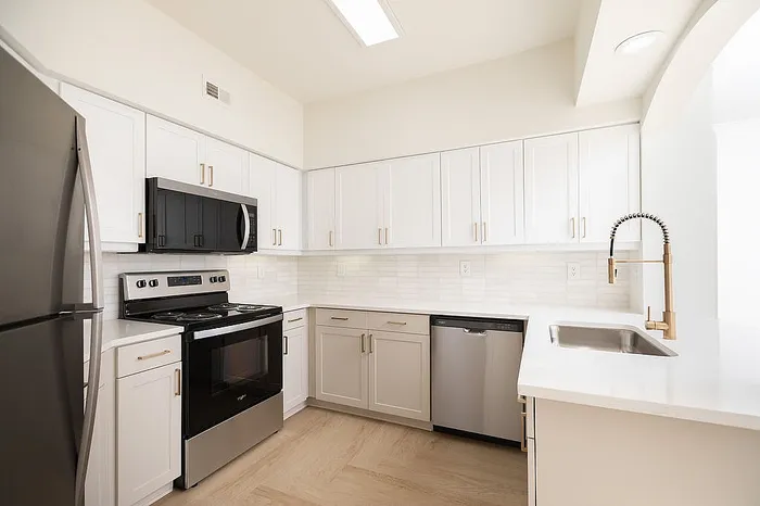 Modern kitchen with sleek stainless steel appliances, elegant white cabinetry, and stylish gold fixtures, offering a contemporary and spacious feel.