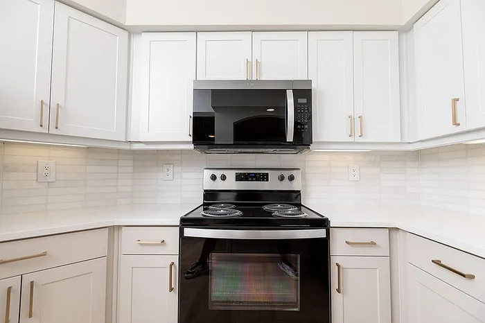 Modern kitchen with sleek white cabinetry, state-of-the-art stainless steel appliances, and elegant tile backsplash.