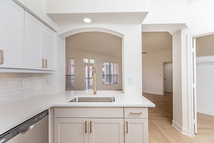 Chic open-plan kitchen with elegant white cabinetry, modern fixtures, and sunlit spacious living area views.