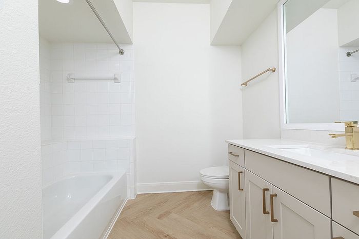 Bright modern bathroom featuring a clean bathtub, sleek white vanity with ample storage, and a large mirror, creating a refreshing and inviting space.