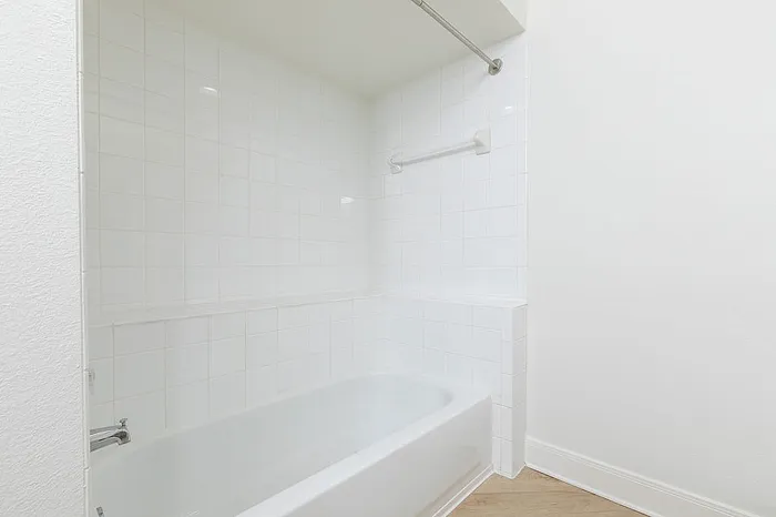 Bright and modern bathroom with clean white tiles and a sleek bathtub, offering a refreshing and serene atmosphere.