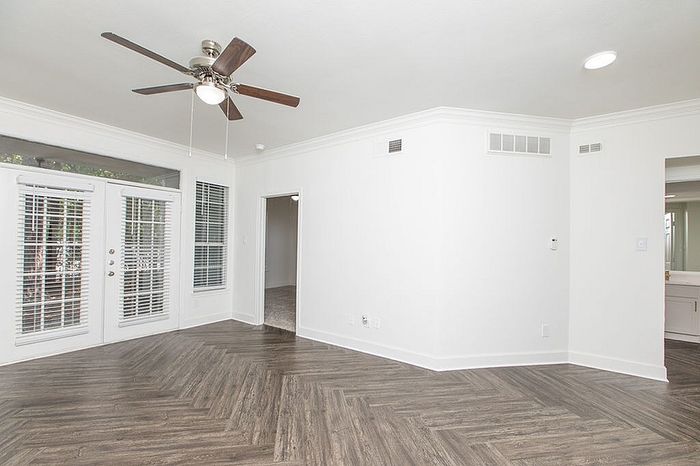 Bright and airy living area with elegant wood flooring and large windows, offering a modern open space ideal for entertaining.