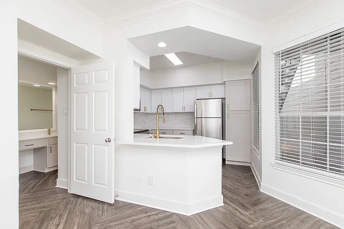 Bright and modern kitchen with sleek white cabinets, stainless steel appliances, and elegant wood flooring.