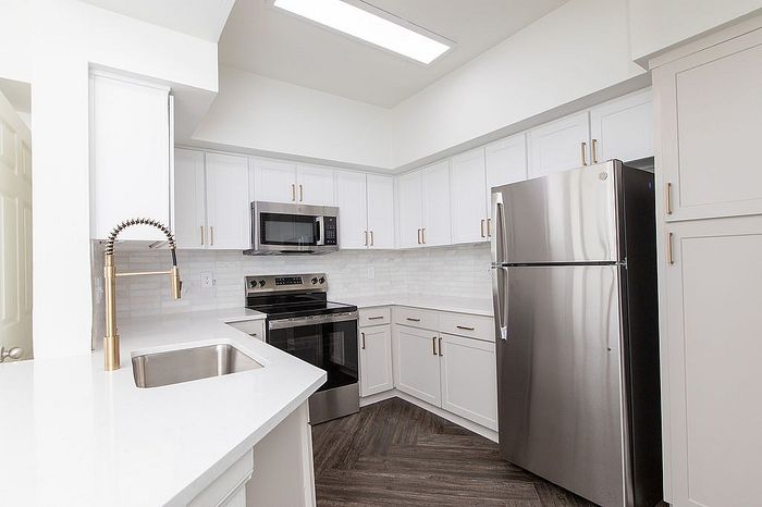 Modern kitchen with sleek stainless-steel appliances, elegant white cabinetry, and stylish gold fixtures, offering a bright and contemporary cooking space.
