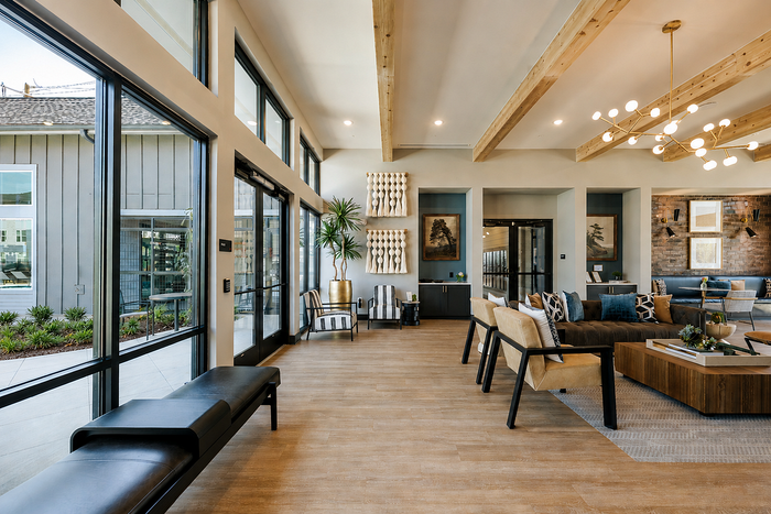 Inviting and spacious living area with modern decor, large windows, and stylish wooden ceiling beams, perfect for entertaining or relaxation. Abundant natural light enhances the sleek, contemporary design.