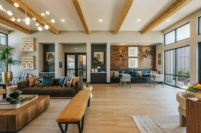 Elegant living area featuring modern decor, plush seating, exposed brick accents, and large windows for abundant natural light.