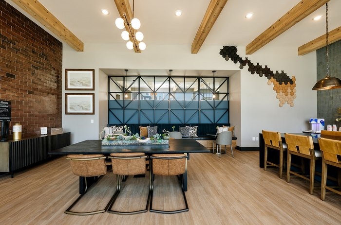 Chic community lounge with modern industrial design, featuring stylish furniture, a long communal table, and artistic wall accents.