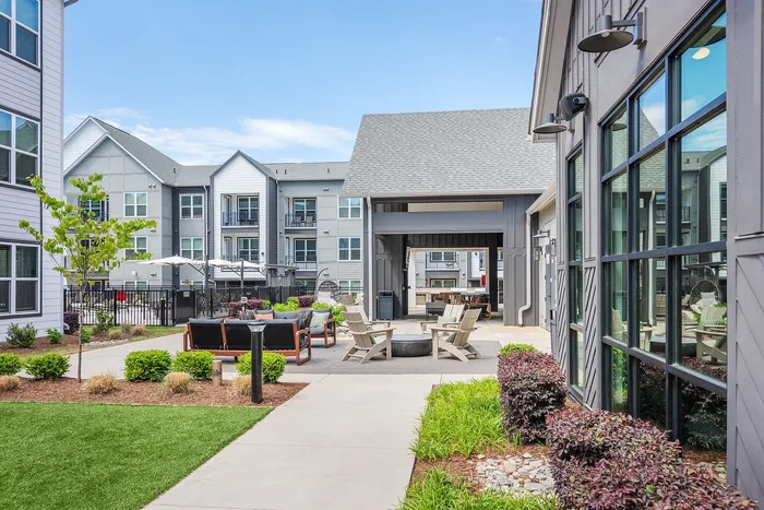 Modern apartment complex courtyard featuring luxurious outdoor seating, vibrant landscaping, and stylish architecture.
