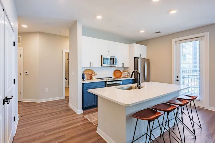 Modern kitchen with sleek white cabinets, stainless steel appliances, and a stylish island with elegant bar stools.