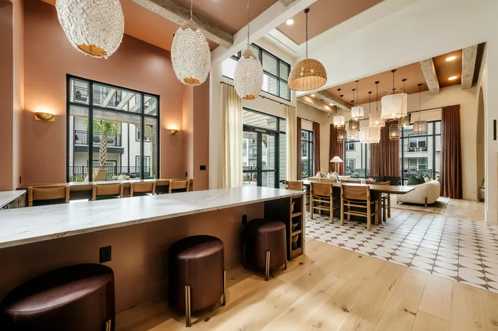 Elegant open-concept living and dining area featuring stylish pendant lighting, warm wood flooring, and expansive windows with a modern design.