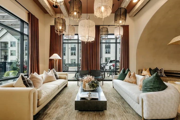 Elegant living room with plush sofas, stylish lighting, and large windows offering serene views of the outdoors.