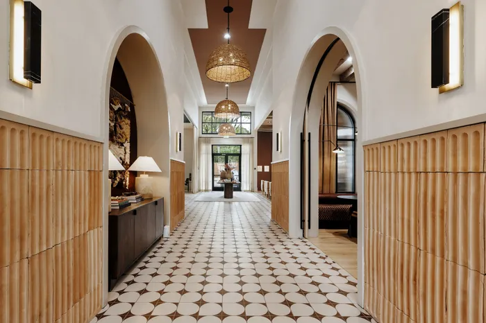 Inviting hallway with elegant archways and modern lighting, leading to a bright, spacious living area.