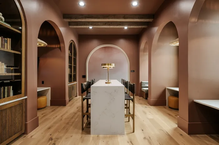 Elegant dining nook with warm earth tones, arched doorways, and a sleek marble table with plush seating beneath stylish lighting.