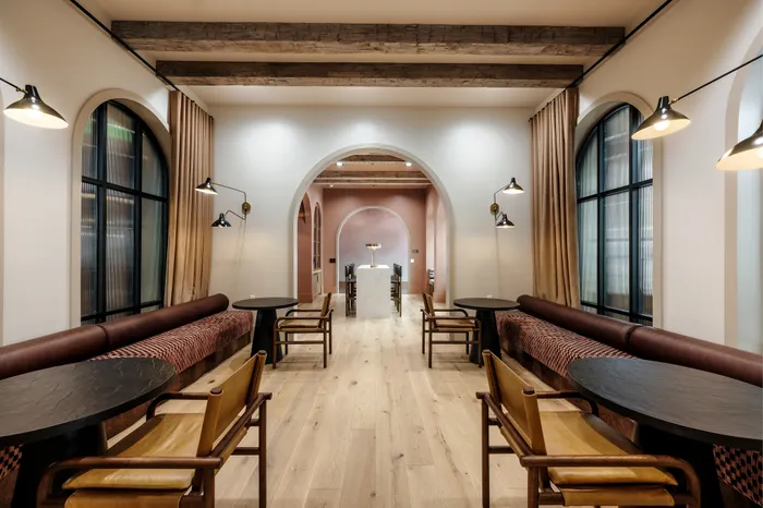 Chic dining area featuring elegant arched doorways, warm wood flooring, and stylish leather seating with contemporary lighting.