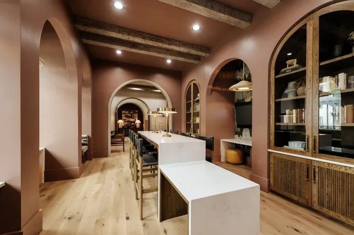 Elegant apartment interior with warm accents, featuring a long marble top island, stylish lighting, and arched doorways creating a cozy ambiance.