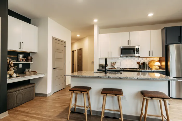 Modern kitchen with sleek white cabinetry, granite countertops, and stylish bar seating for a contemporary living experience.