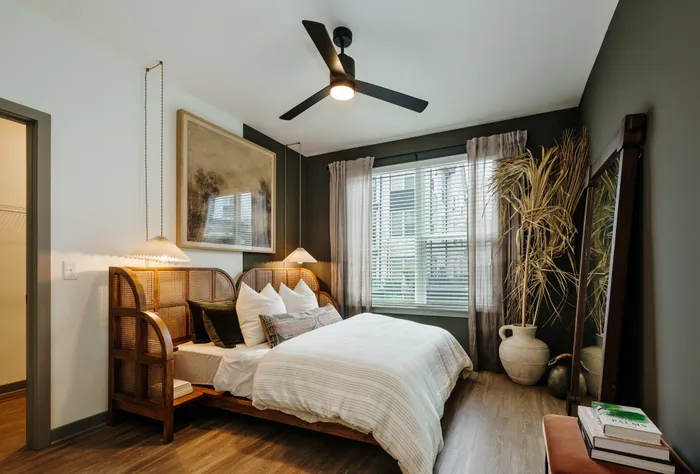 Elegant bedroom with a cozy bed, stylish wooden headboard, and large window letting in natural light, creating a serene and inviting atmosphere.