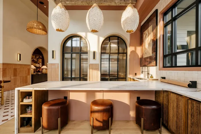 Chic sunlit kitchen featuring elegant arched windows, warm terracotta tones, and stylish pendant lighting for modern living.