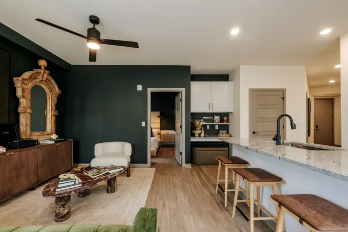 Modern apartment interior with sleek kitchen island, stylish living area, and inviting bedroom entrance.