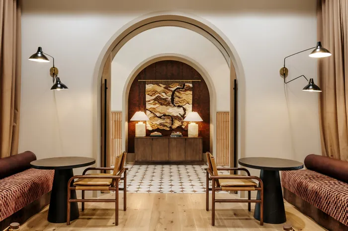 Elegant interior featuring archway with intricate tapestry, modern lighting, and cozy sitting area.