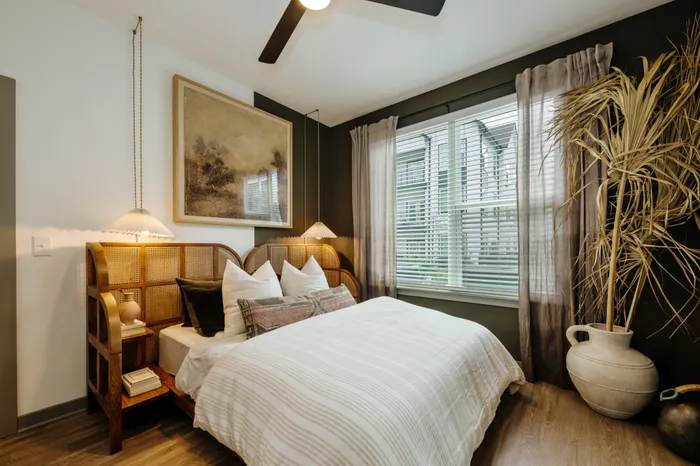 Inviting bedroom with cozy bed, ambient lighting, and large window offering natural light, complemented by elegant decor and stylish flooring.