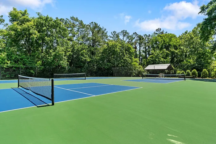 Scenic view of modern outdoor tennis courts surrounded by lush greenery, perfect for active lifestyle enthusiasts.