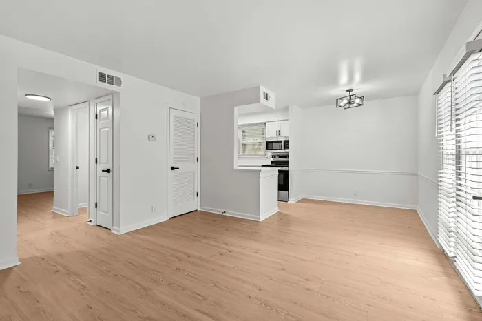 Bright and modern open living space with sleek hardwood floors, contemporary lighting, and direct access to a stylish kitchen.